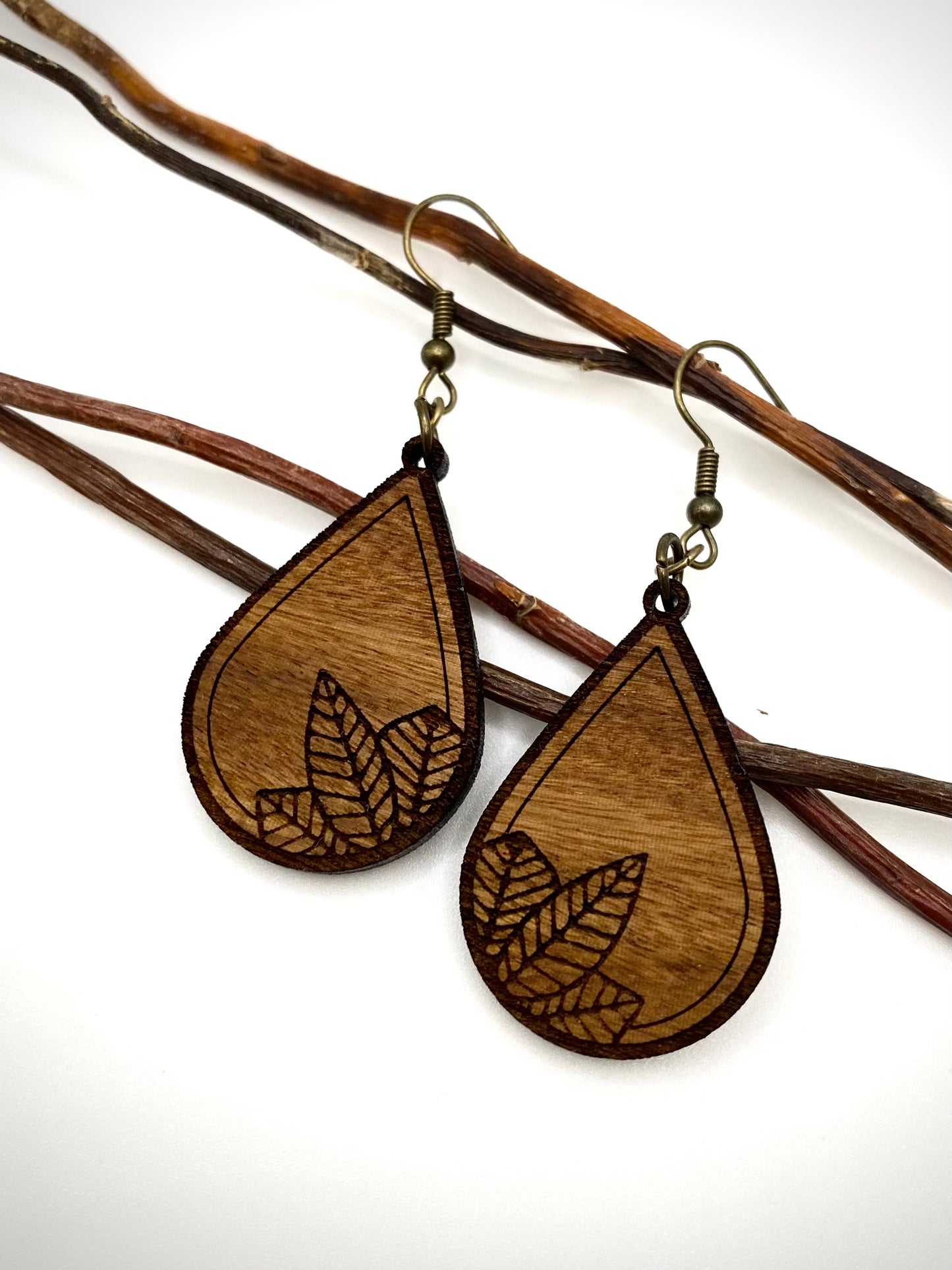 leaf engraved wood earrings hanging on a thin branch